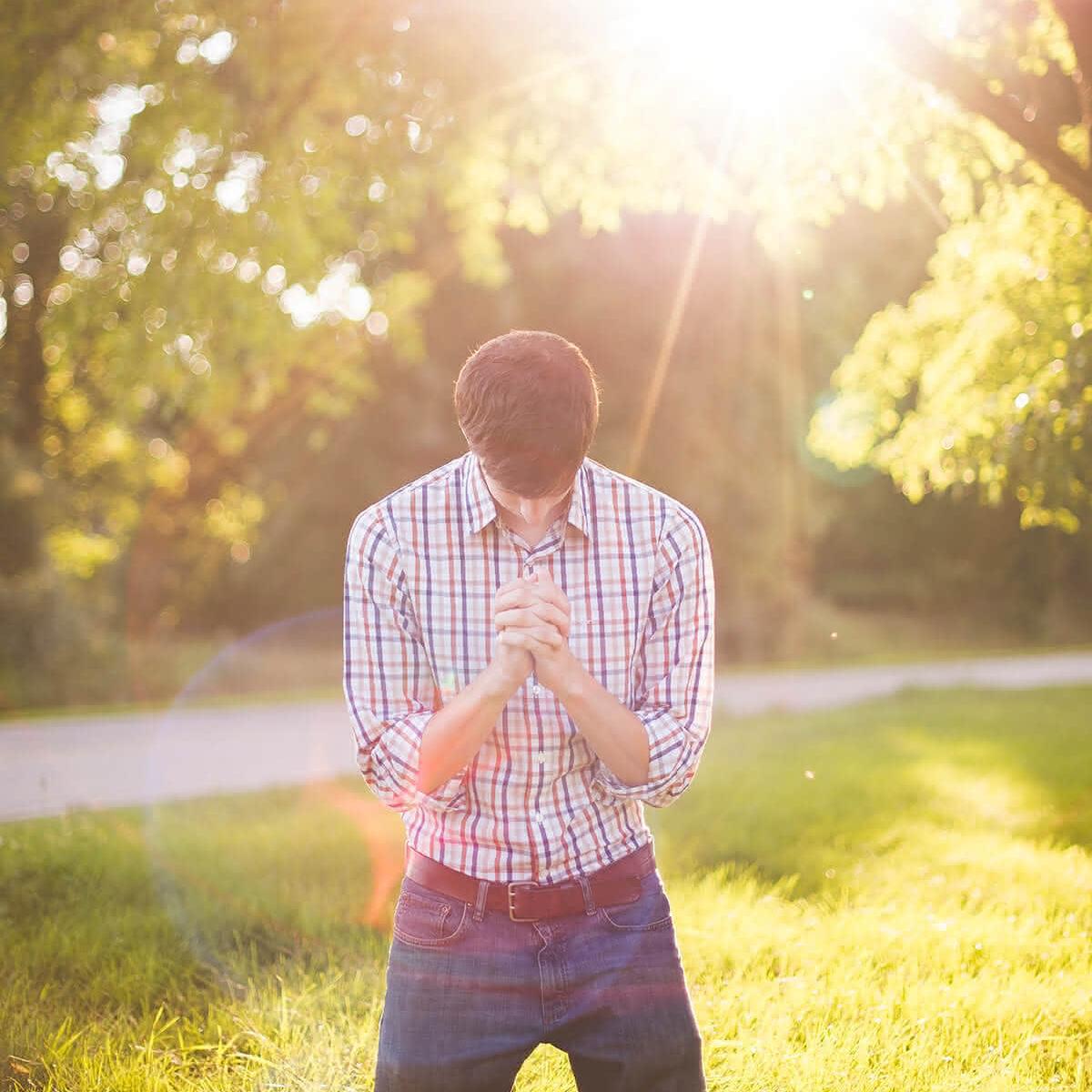 Betender auf einer Wiese, im Hintergrund scheint die Sonne